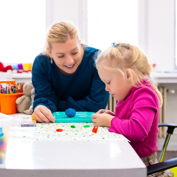 A behaviour analyst working with a young girl at a table