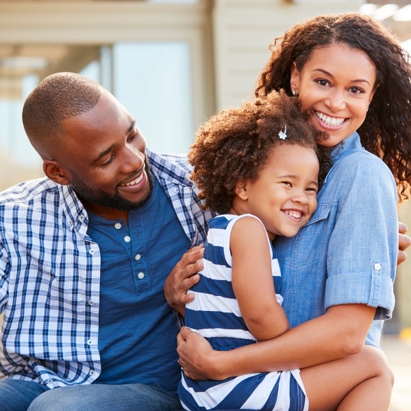 A mother, father and daughter sharing a hug